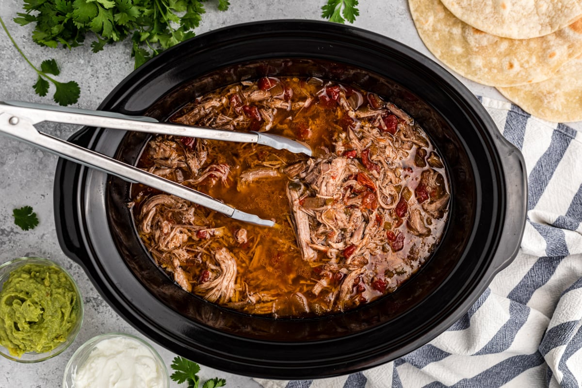 overhead shot of shredded pork burrito filling in a slow cooker.