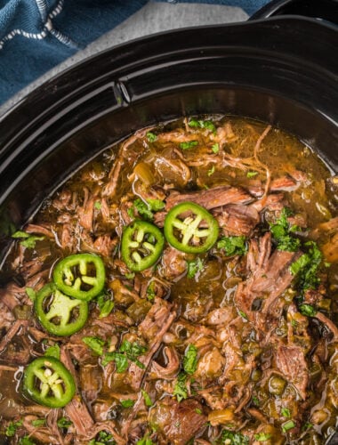overhead of salsa verde beef in a black crockpot.