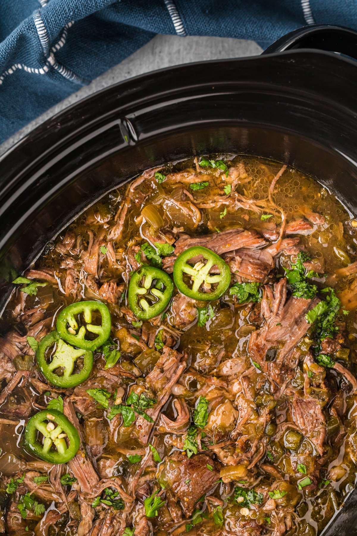 overhead of salsa verde beef in a black crockpot.