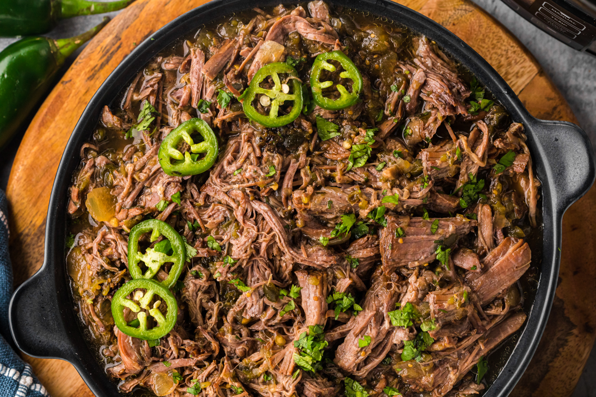 close-up overhead of salsa verde beef in a black serving dish.