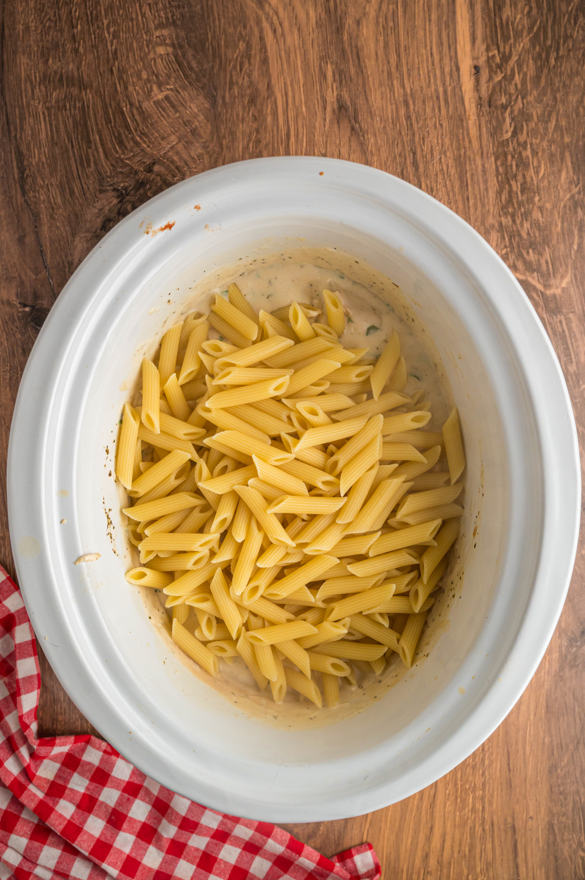 cooked penne pasta added to alfredo and chicken in the crockpot.
