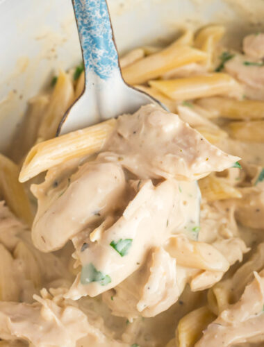 chicken alfredo on a metal spoon coming from a slow cooker.