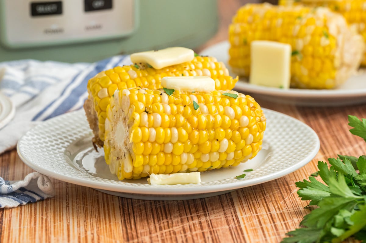 2 pieces of corn in front of a slow cooker.