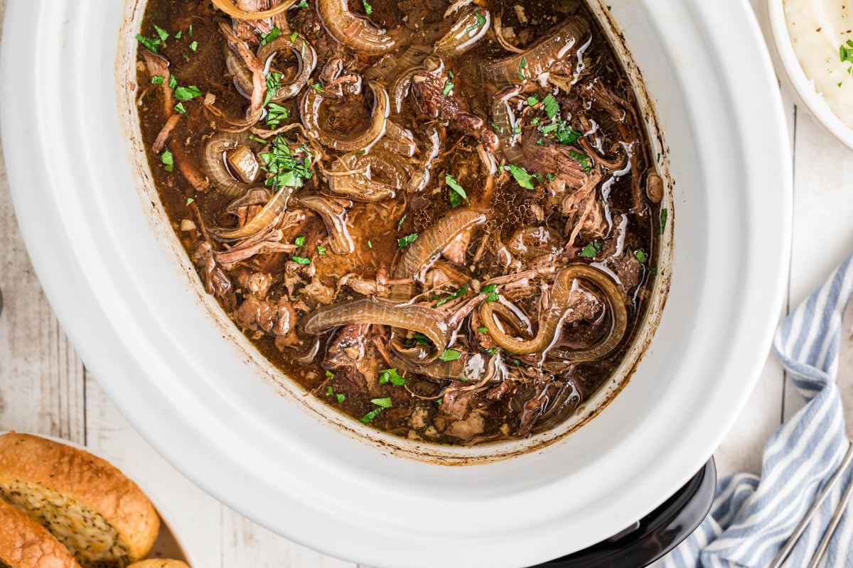 overhead of french onion pot roast in a slow cooker.