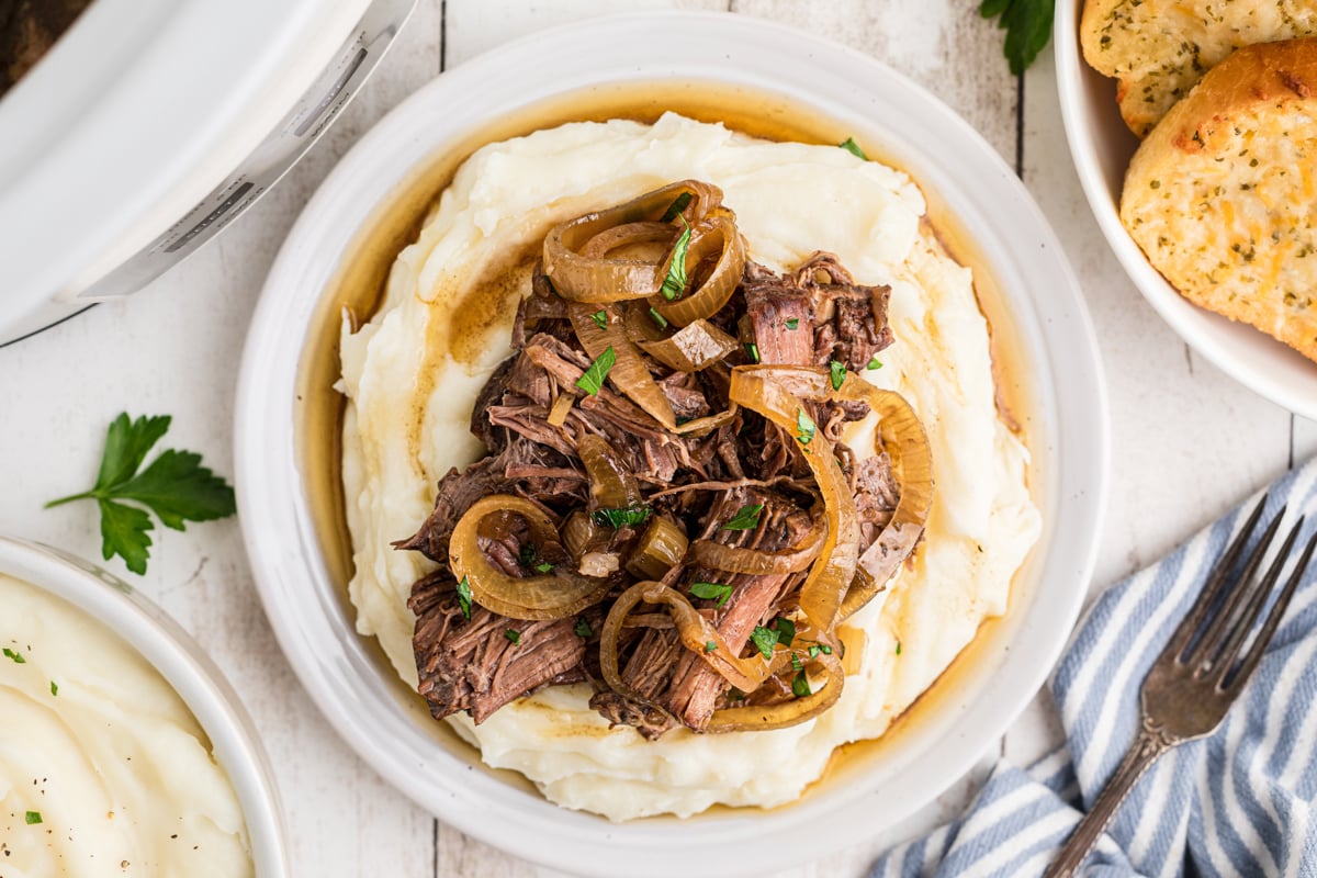 overhead of slow cooker french onion pot roast on top of mashed potatoes.