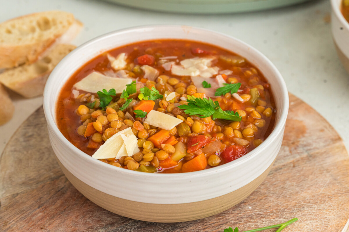 Close up of lentil soup in a bowl with parmesan cheese and parsley.