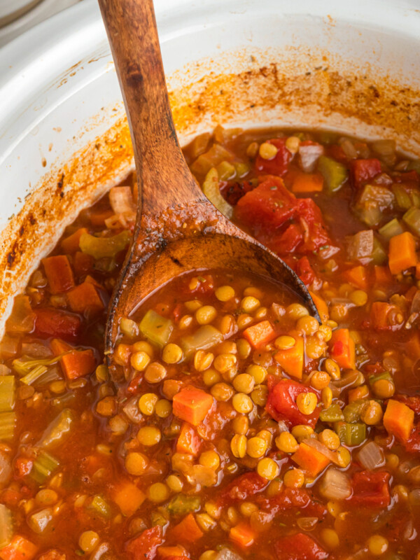 Lentil soup in a slow cooker and a wooden spoon.
