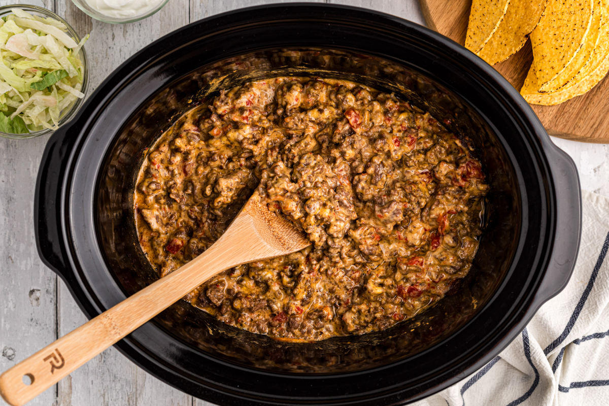 Overhead shot of rotel, ground beef and velveeta in a slow cooker.
