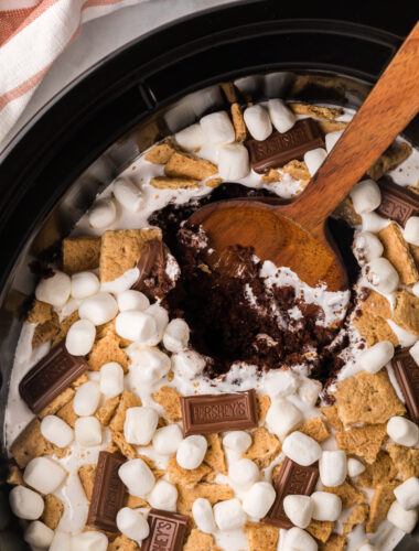 smores cake in a slow cooker with a wooden spoon in it.