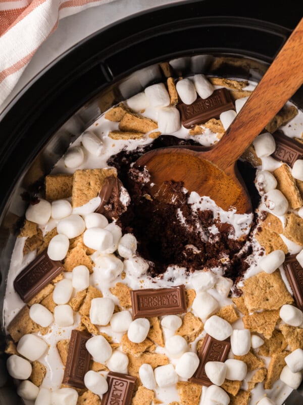 smores cake in a slow cooker with a wooden spoon in it.