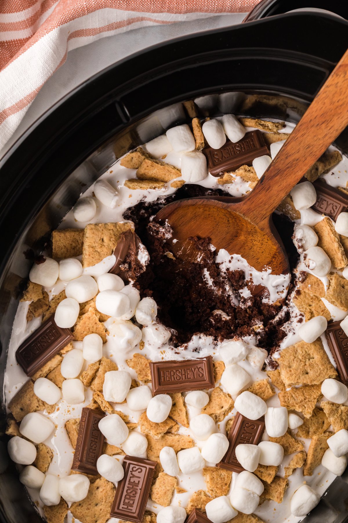 smores cake in a slow cooker with a wooden spoon in it.