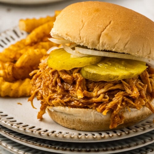 Spicy chicken sandwich on a plate wit fries.
