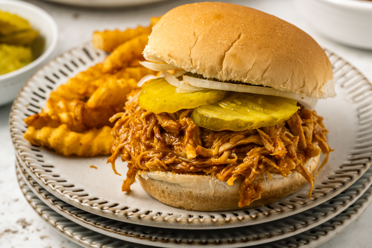 Spicy chicken sandwich on a plate wit fries.