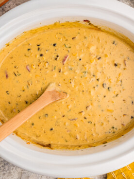 Overhead shot of corn dip with wooden spoon in it.