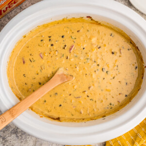 Overhead shot of corn dip with wooden spoon in it.
