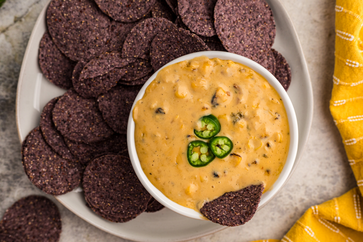 overhead shot of a platter with corn dip and blue corn chips.