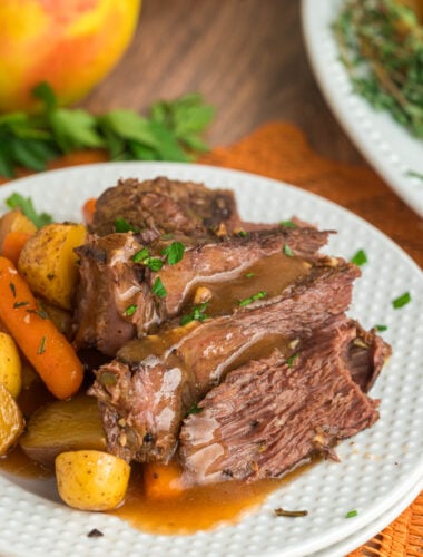 Apple cider pot roast with carrots and potatoes on a plate.