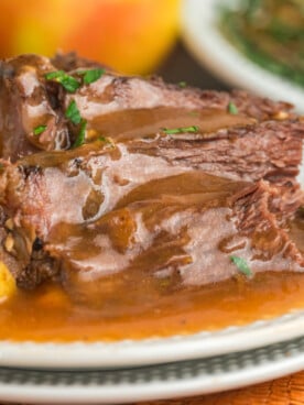 pot roast on a plate with gravy and vegetables.