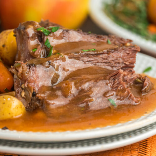 pot roast on a plate with gravy and vegetables.