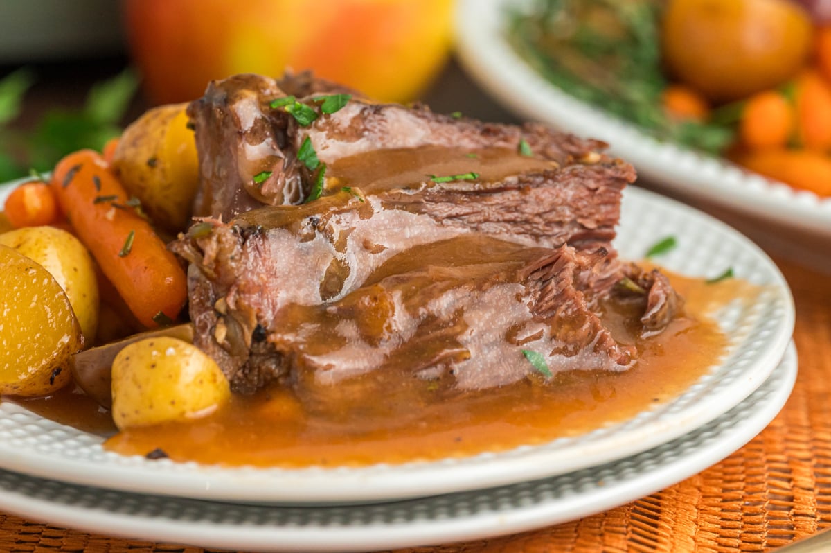 pot roast on a plate with gravy and vegetables.