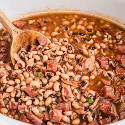 black eyed peas in a slow cooker with a wooden spoon in it.