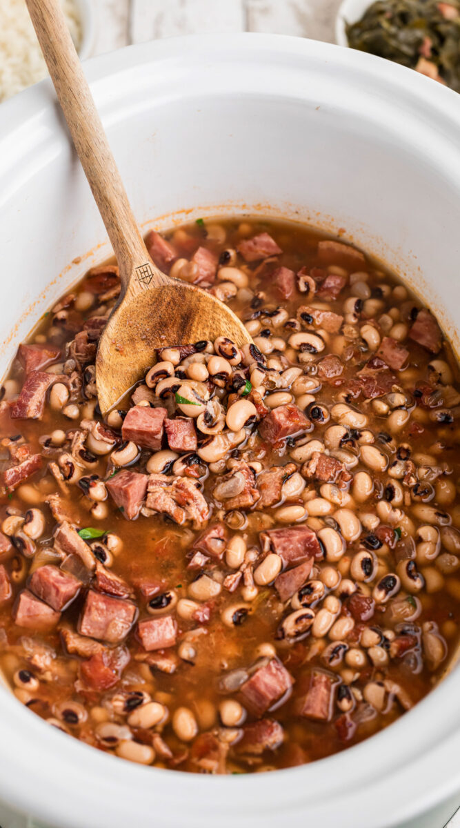Long image of black eyed peas with wooden spoon in it.
