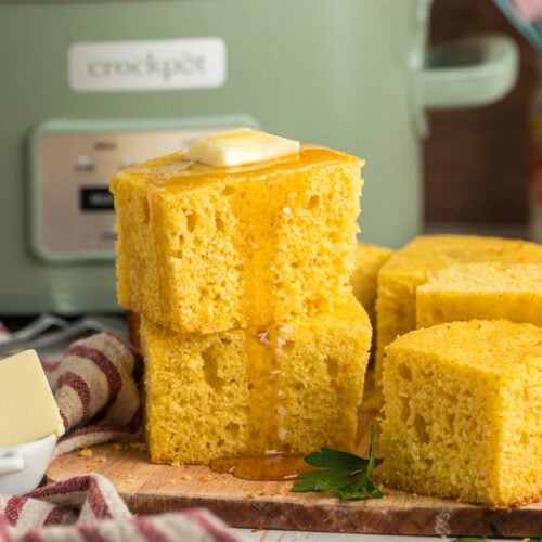 Cornbread in front of the slow cooker with butter on top.