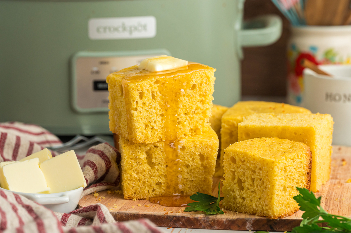 Cornbread in front of the slow cooker with butter on top.