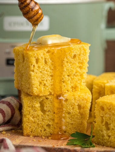2 pieces of cornbread with honey being drizzled over.