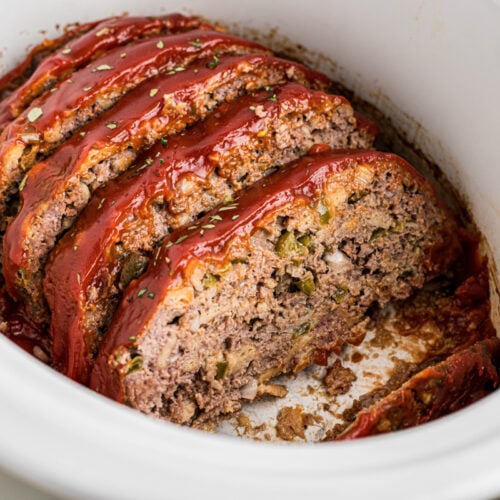 sliced meatloaf with glaze in a white slow cooker.