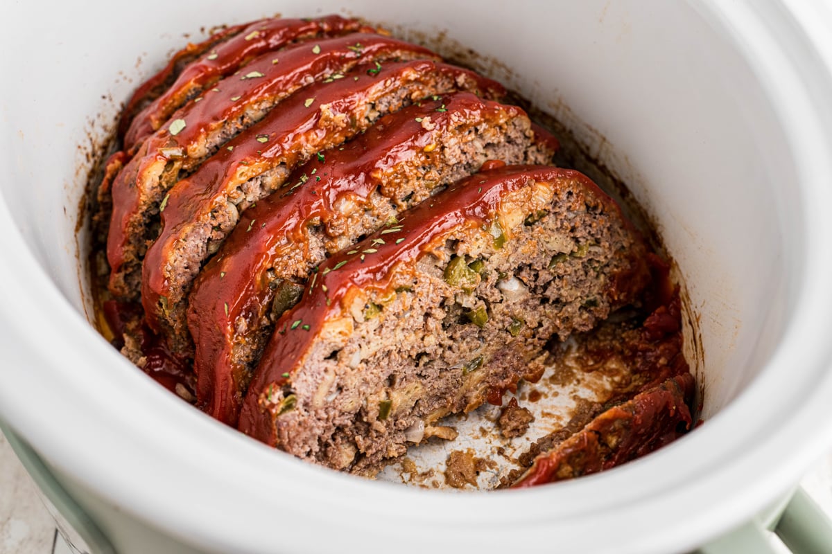 sliced meatloaf with glaze in a white slow cooker.
