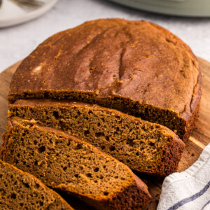 Pumpkin bread on a cutting board in front of a slow cooker.