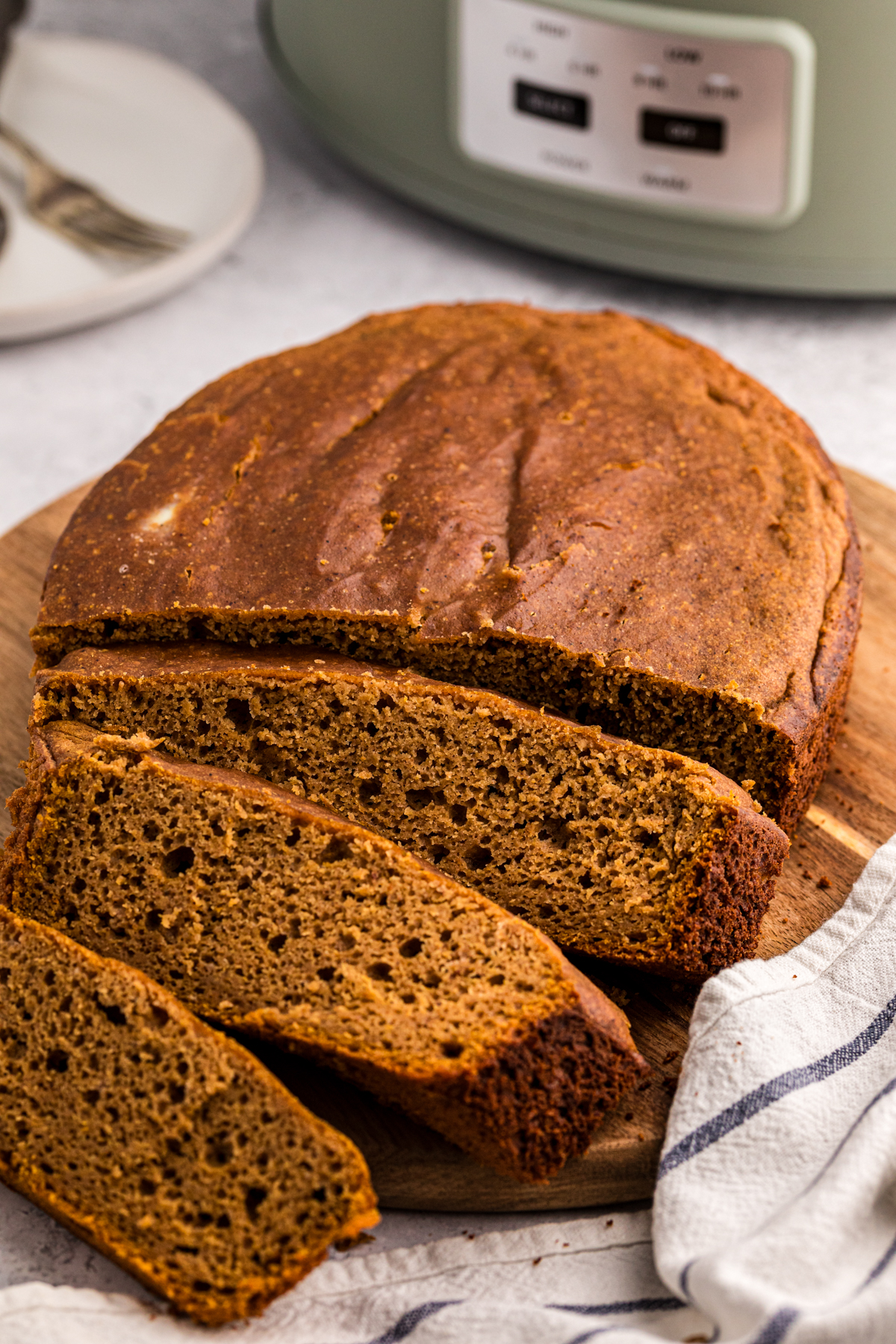 Pumpkin bread on a cutting board in front of a slow cooker.