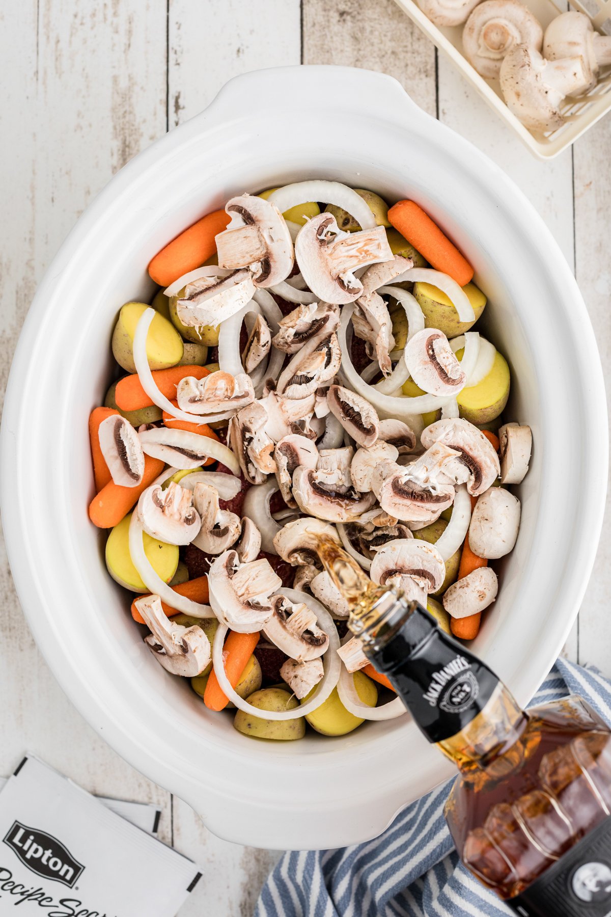 whiskey being poured over a roast and vegeatbles.