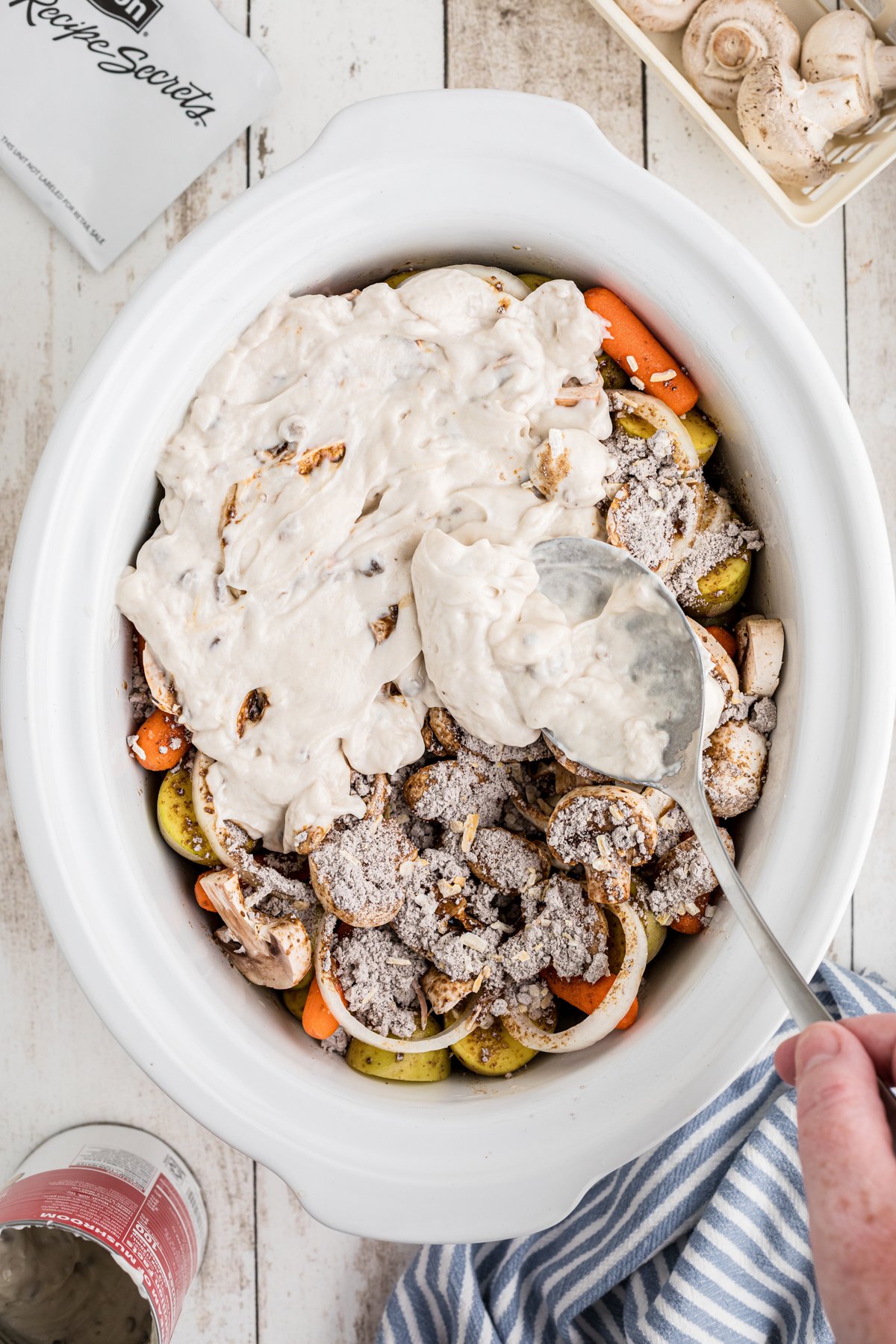 cream of mushroom soup being added on top of the vegetables and roast.