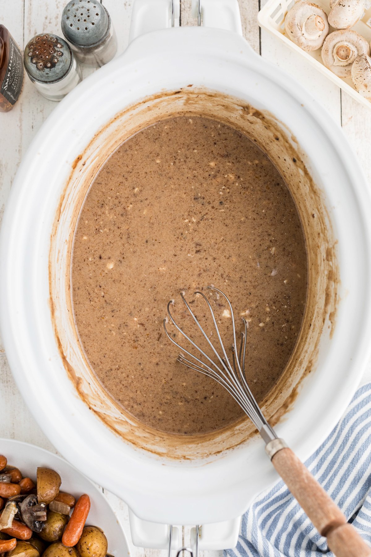Gravy being stirred in a slow cooker.