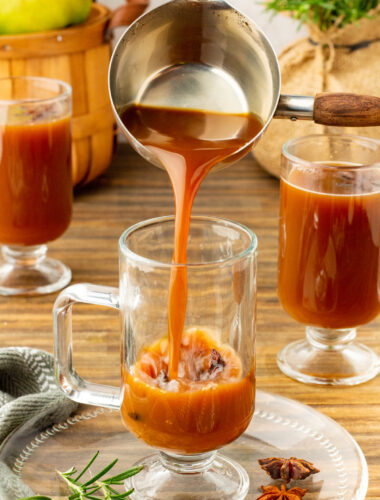 Pear cider being poured into a clear tall mug.