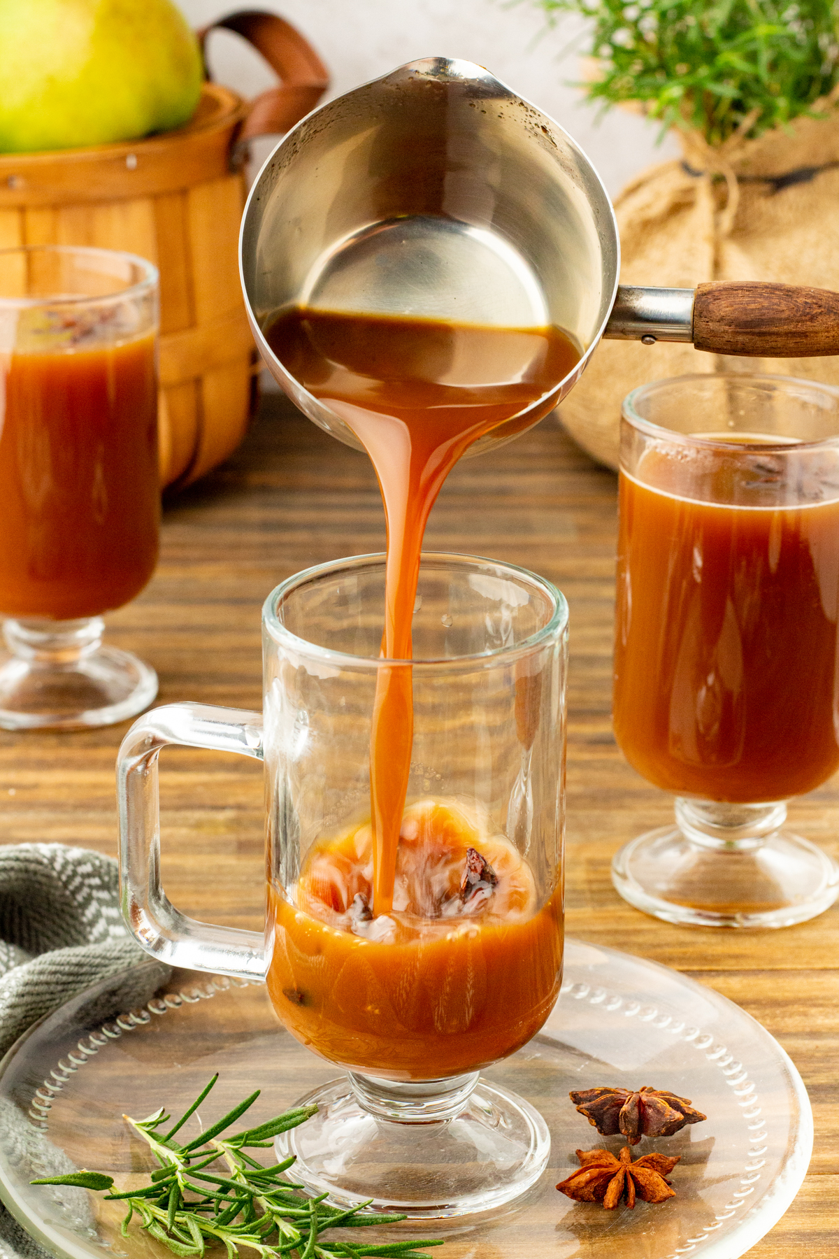 Pear cider being poured into a clear tall mug.