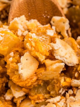 close up of pineapple casserole in a slow cooker with wooden spoon in it.