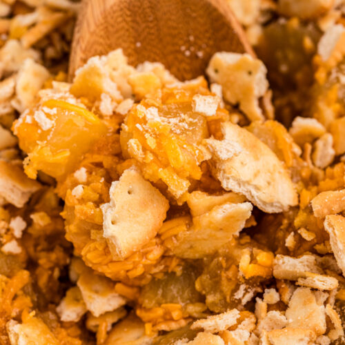 close up of pineapple casserole in a slow cooker with wooden spoon in it.