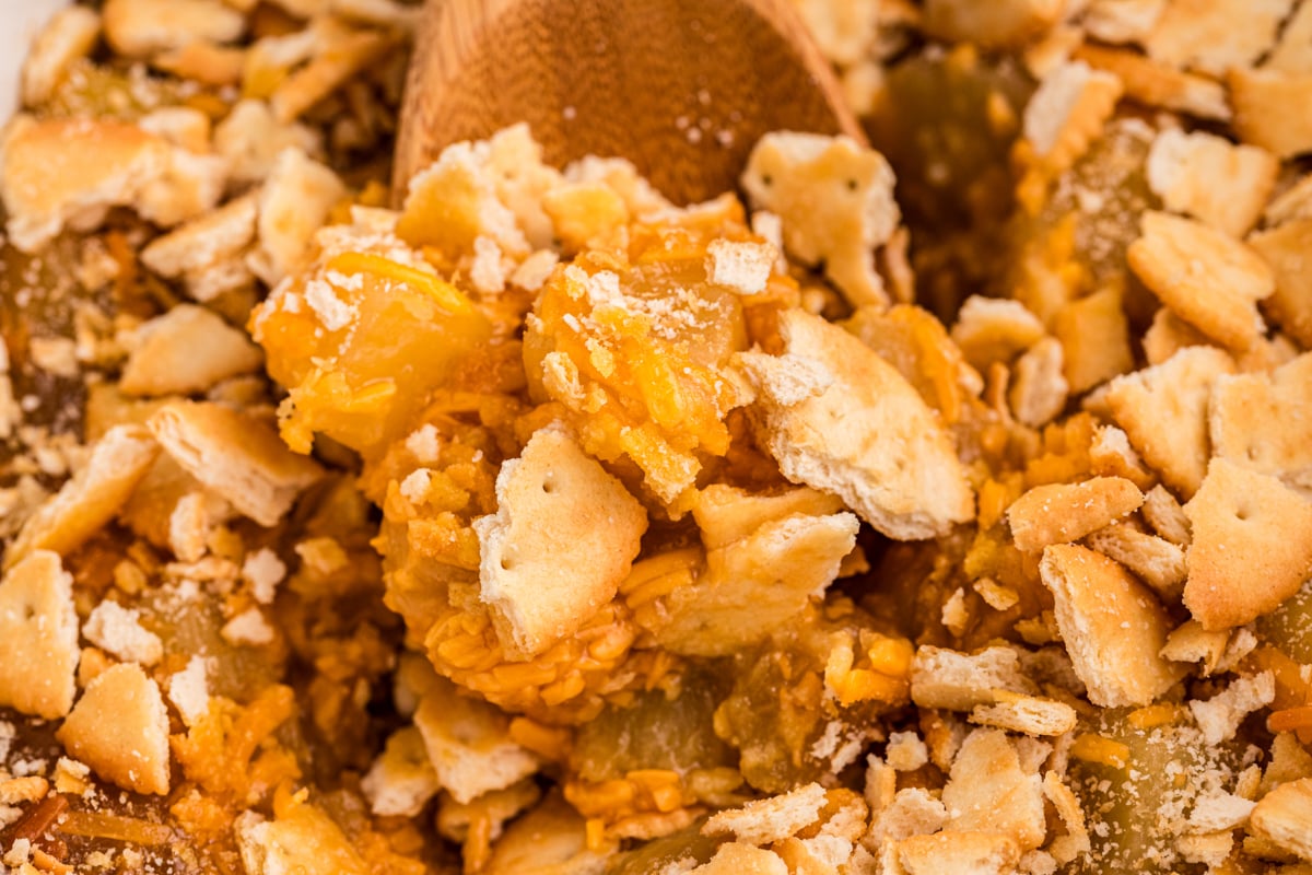 close up of pineapple casserole in a slow cooker with wooden spoon in it.