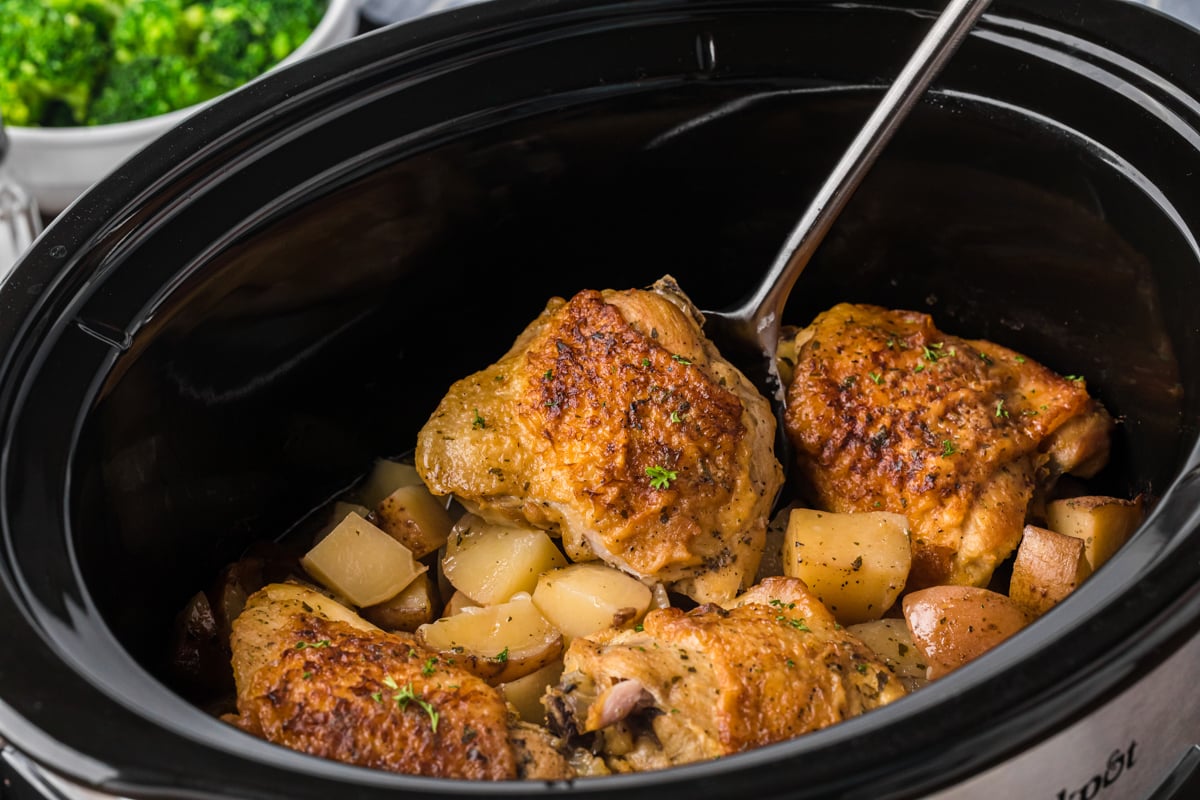 side view of chicken thighs and red potatoes in a slow cooker.