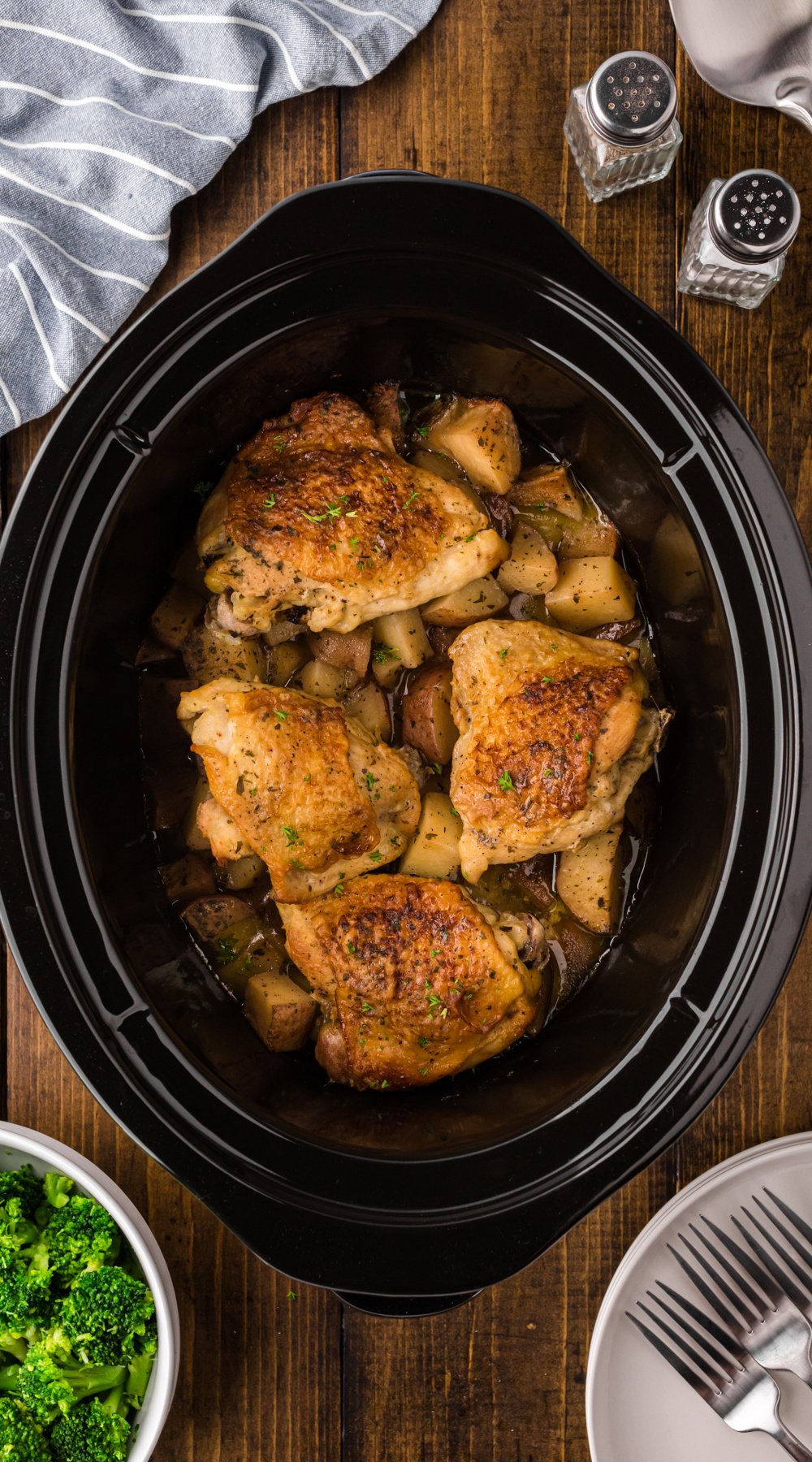 Long image of chicken thighs and potatoes in a slow cooker.