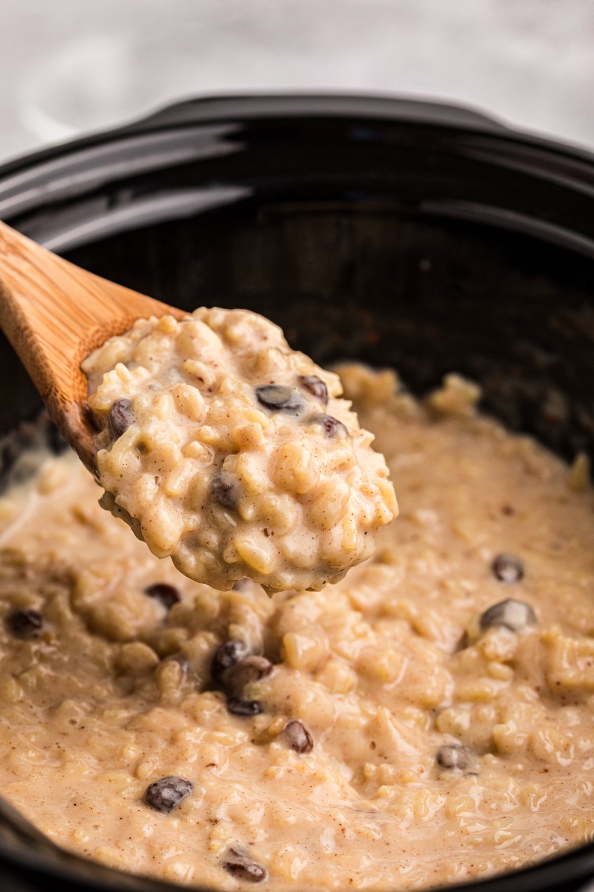 Rice pudding on a spoon coming from a crockpot.