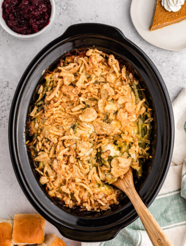 thanksgiving casserole in a slow cooker with pie and cranberry sauce on the side.