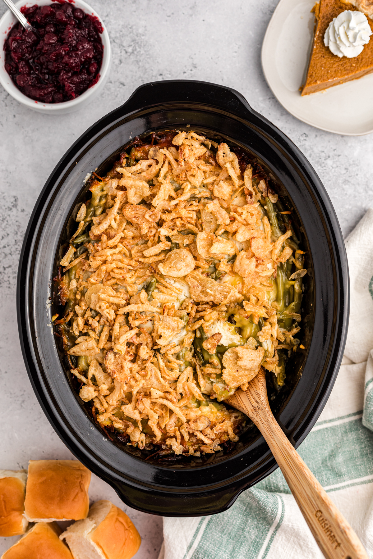 thanksgiving casserole in a slow cooker with pie and cranberry sauce on the side.