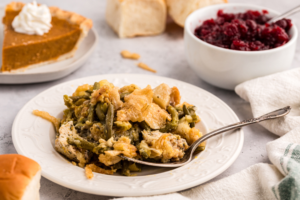 plate of thanksgiving casserole with pie and cranberry sauce in background.