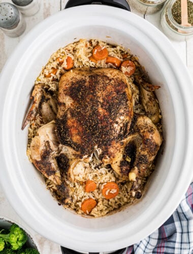 A whole chicken in a slow cooker with rice and vegetables.