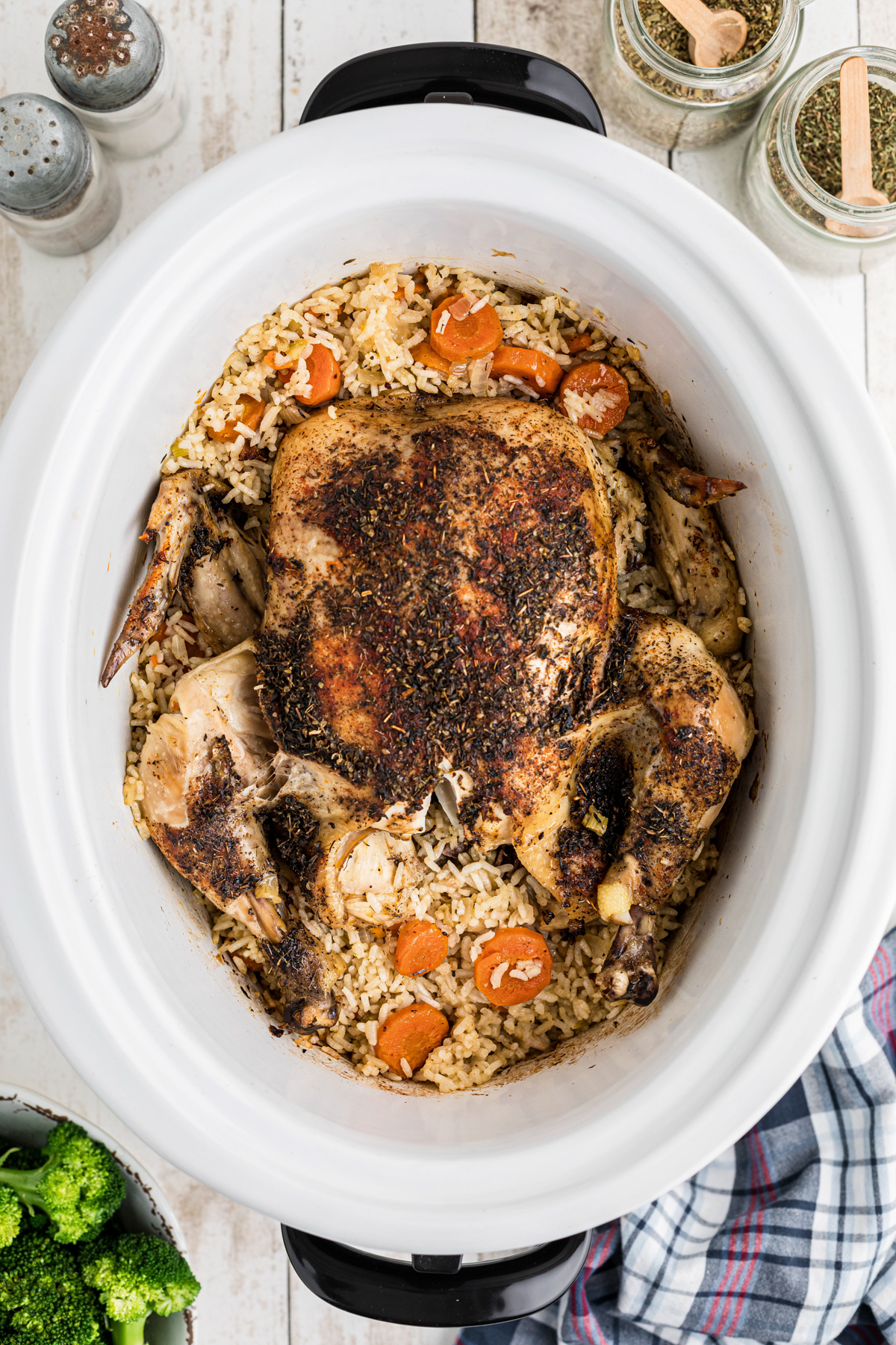 A whole chicken in a slow cooker with rice and vegetables.