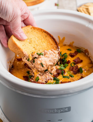 dipping garlic bread into crockpot barbecue chicken dip.